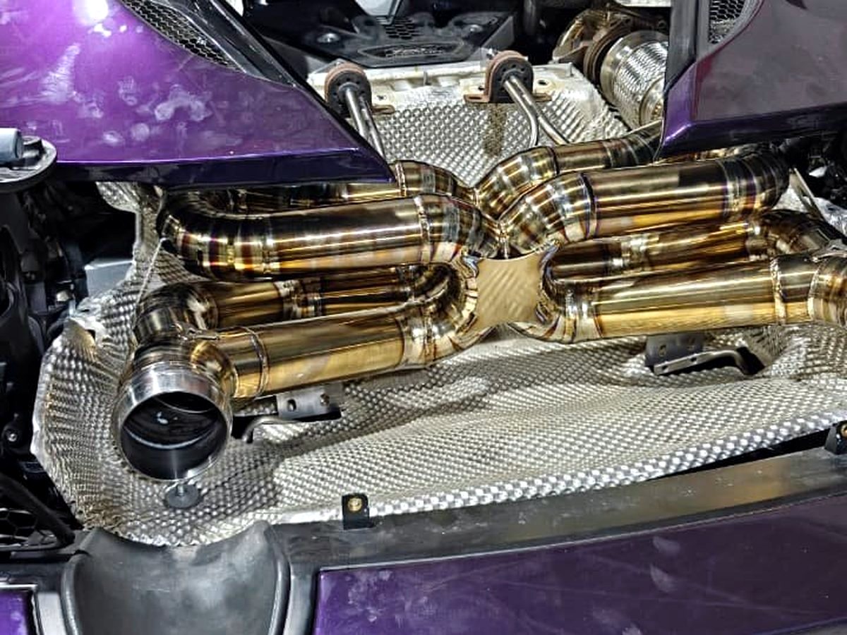 McLaren 720S engine bay with OUCHI titanium dual X-pipe exhaust, gold heat tint — customer installation