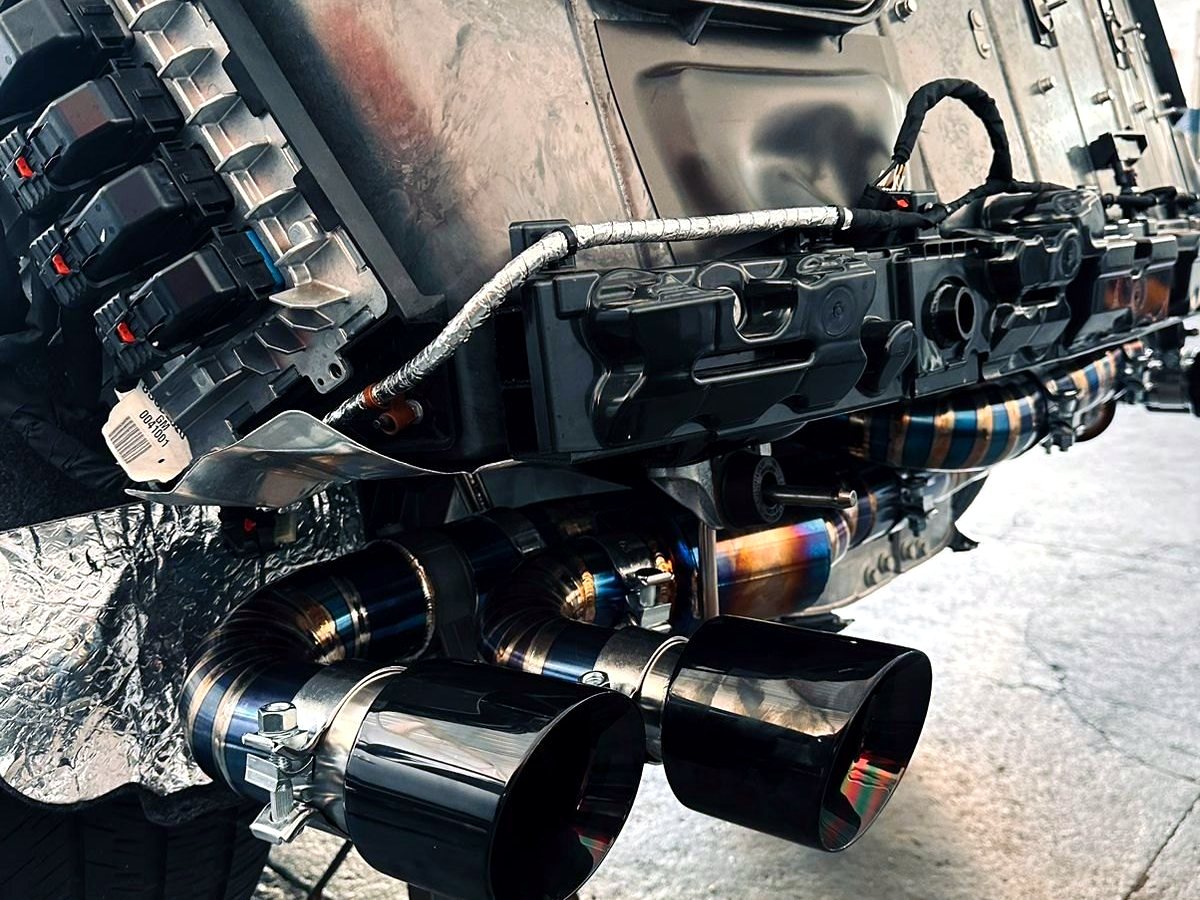 Corvette C8 rear with OUCHI titanium X-pipe exhaust and black quad tips — customer installation