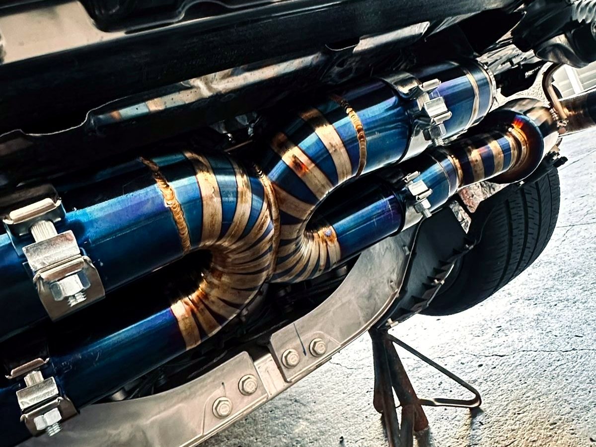 Corvette C8 underbody — OUCHI titanium X-pipe center section with heat-tinted welds, customer installation