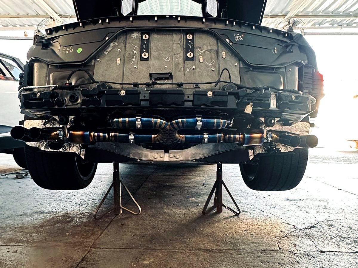 Corvette C8 on the lift with full OUCHI titanium exhaust visible underbody — customer installation