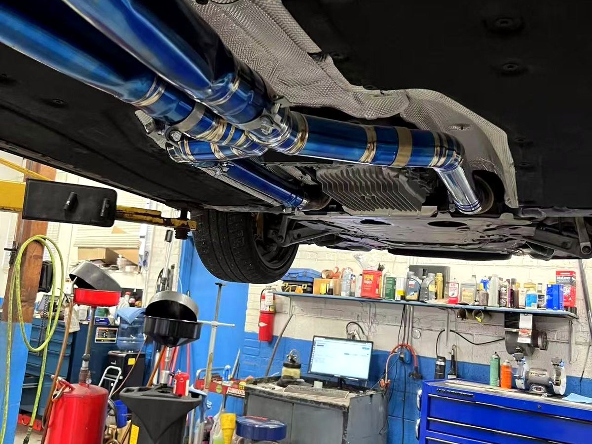 BMW M5 G90 titanium mid-rear exhaust side view in the workshop — customer installation