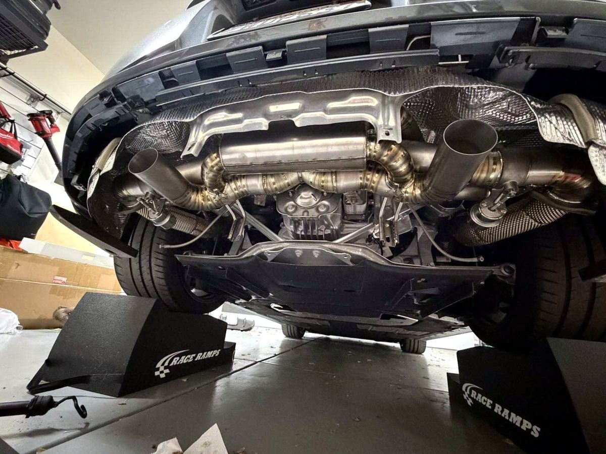 T304 stainless twin mid-silencer section fitted under a customer car on the lift — customer installation