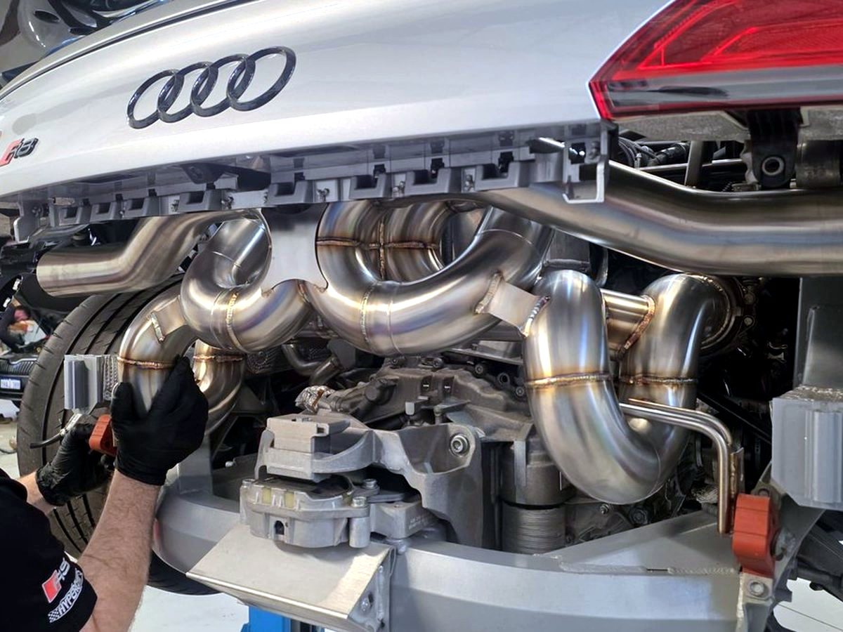 Audi R8 V10 underbody — OUCHI dual X-pipe T304 stainless exhaust routing during installation — customer photo