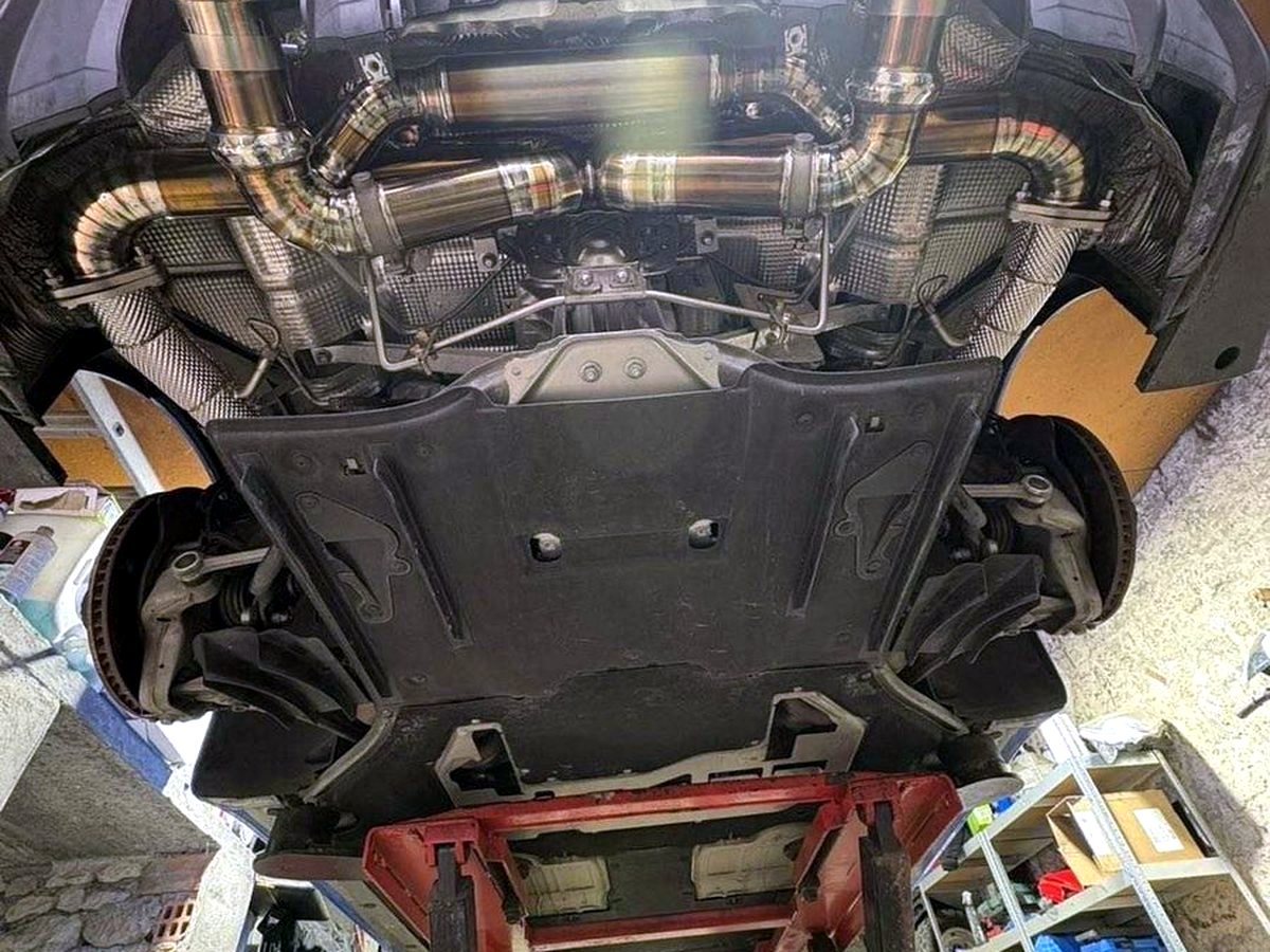 Titanium quad-outlet exhaust underbody — heat-tinted OUCHI welds — customer installation detail